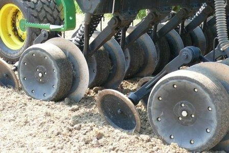 Close-up of a farming equipment's disc blades working on the soil, preparing it for planting seeds. No landmarks or historical buildings visible.